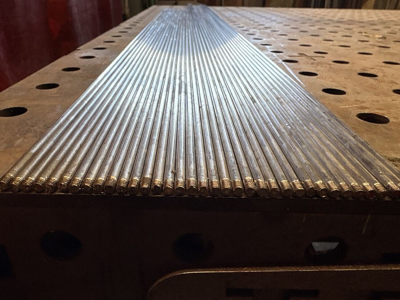 Stainless guardrail infill rods threaded on the fixture table, 1 of 2
